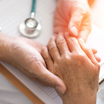 a medical professional holding an elderly person's hand