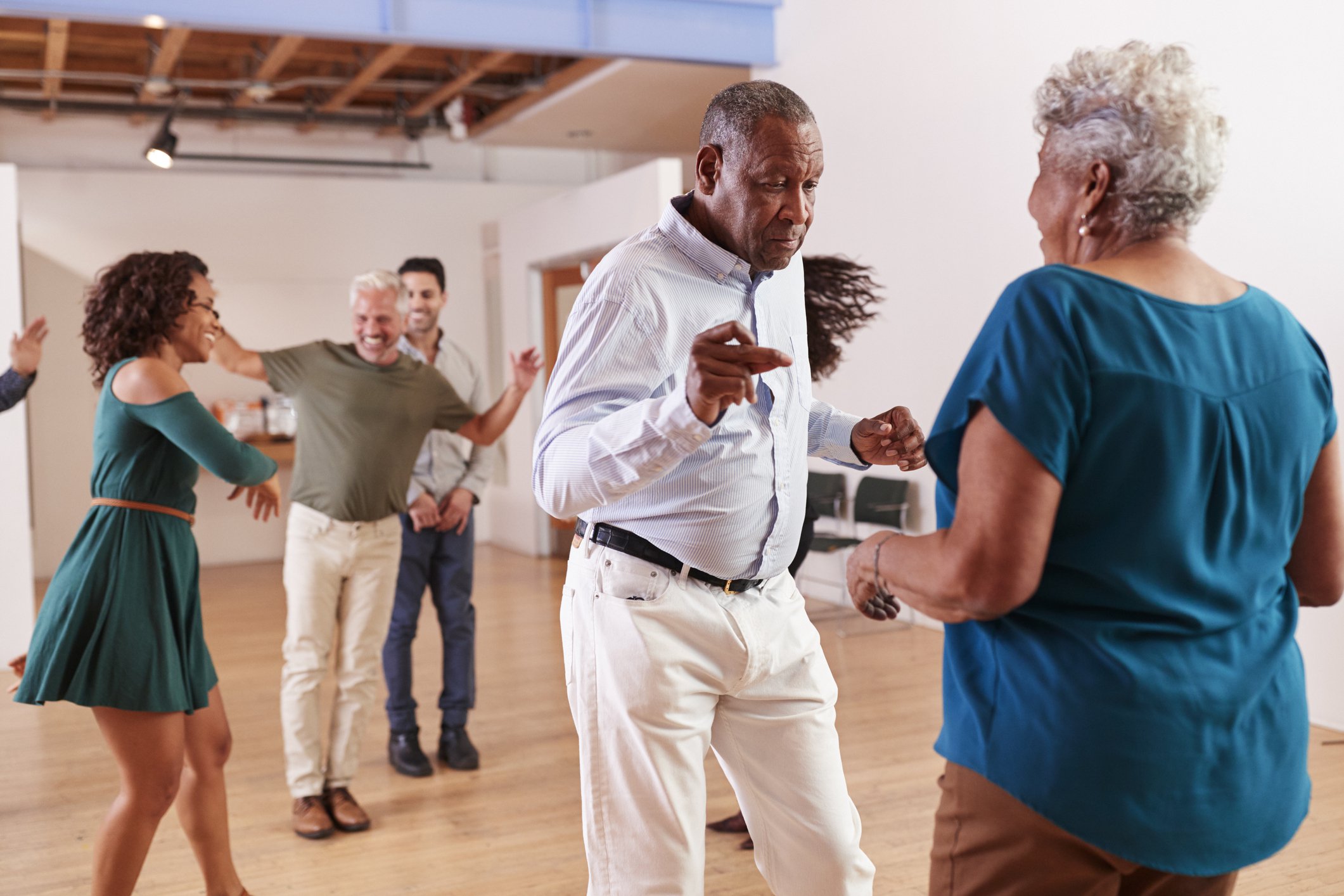 Seniors are dancing in a large, light room — an excellent aerobic exercise for how to slow glaucoma in seniors
