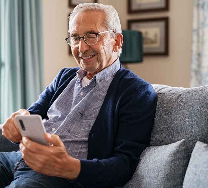 smiling older man using his smartphone at home