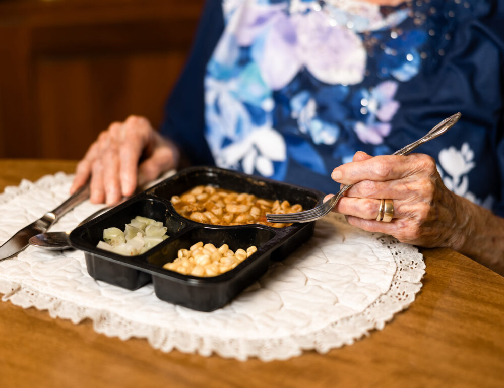 elderly woman enjoying her meal from Meals on Wheels