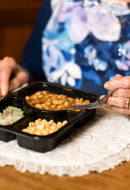 elderly woman enjoying her meal from Meals on Wheels