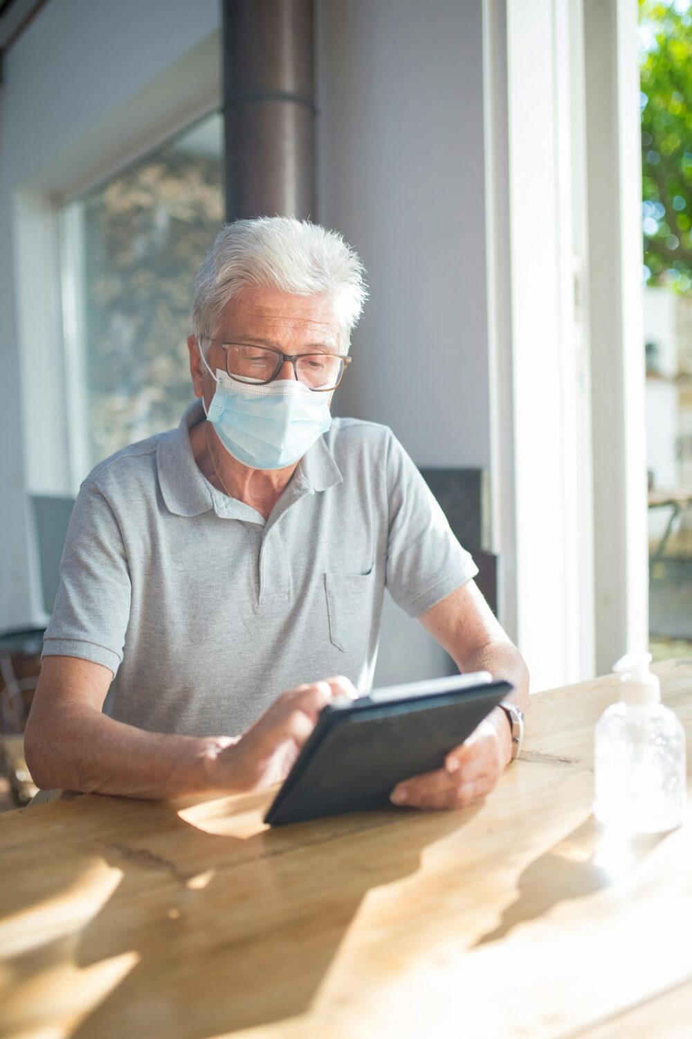 elderly man wearing a face mask and using a tablet device