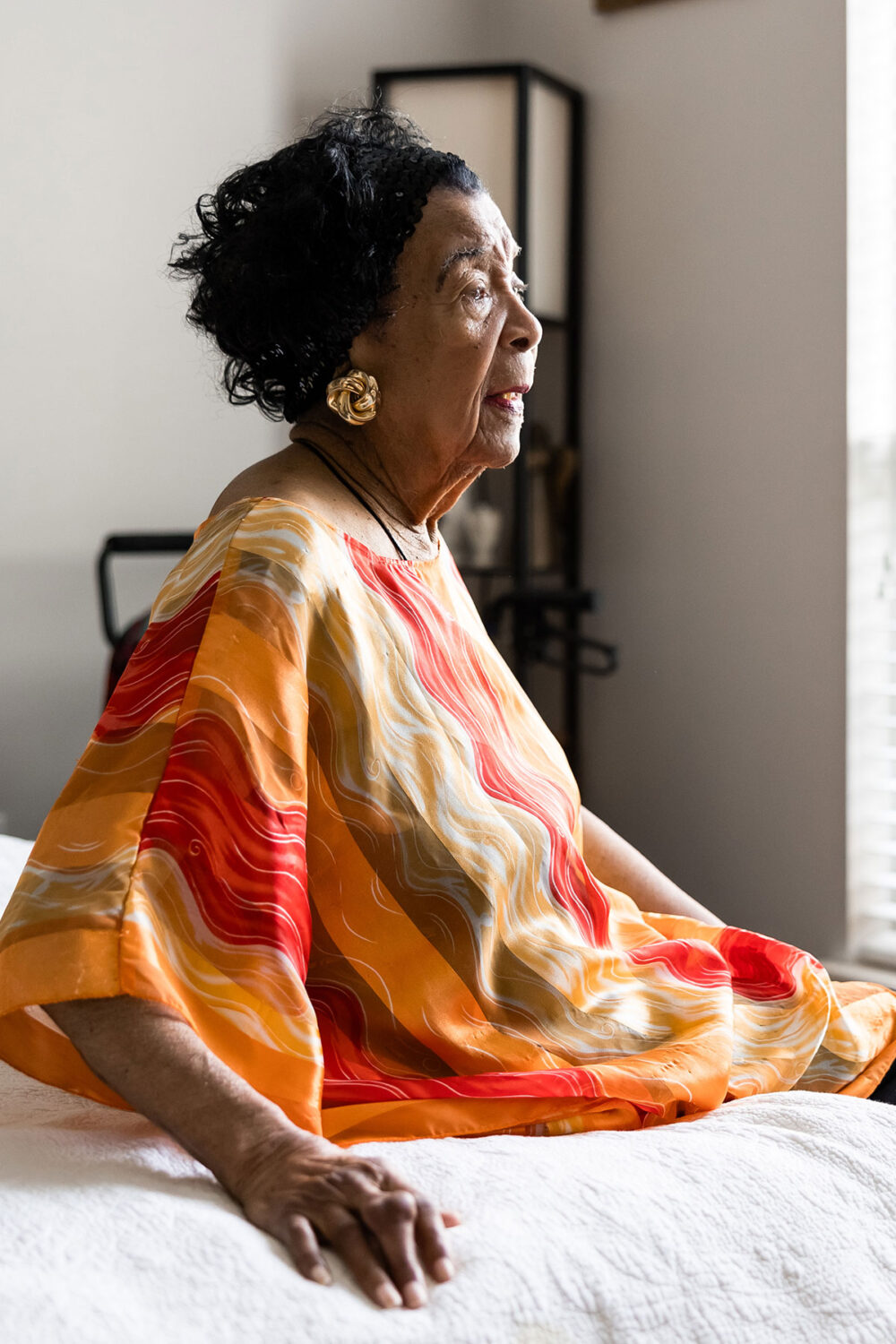 elderly woman sitting on her bed at home
