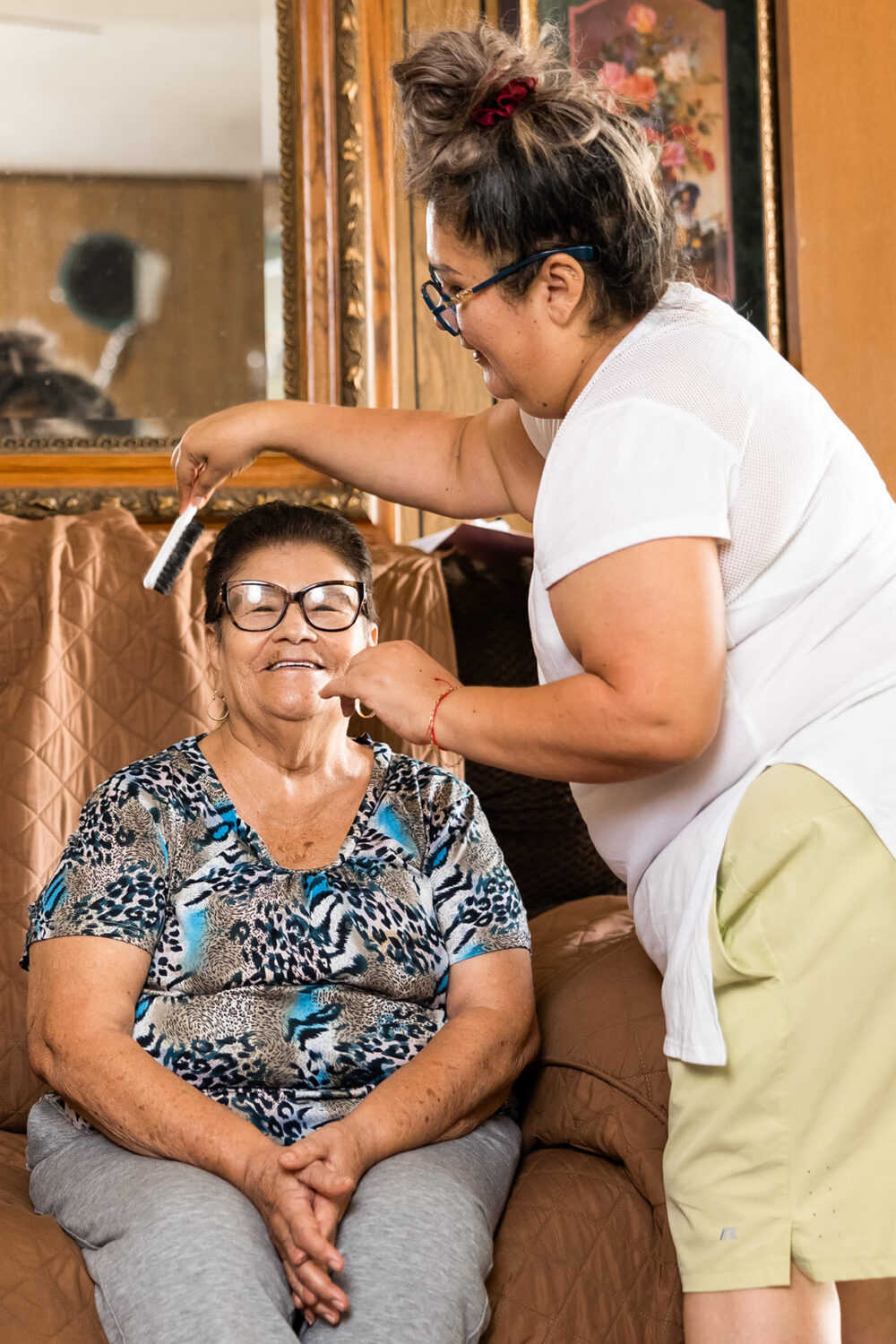 caregiver brushing the hair of a smiling elderly woman