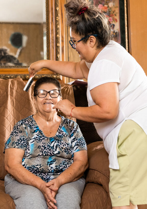 caregiver brushing the hair of a smiling elderly woman