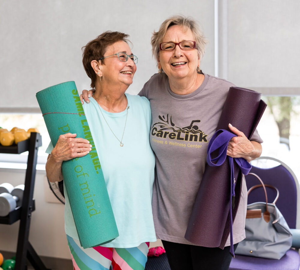 laughing older women holding yoga mats